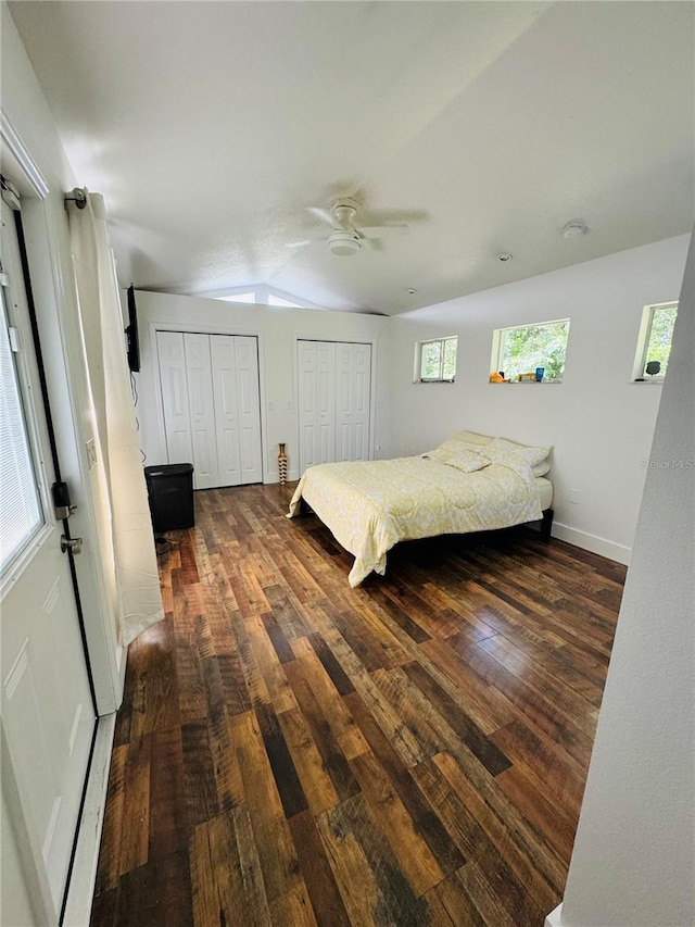 bedroom featuring dark hardwood / wood-style flooring, ceiling fan, vaulted ceiling, and multiple windows