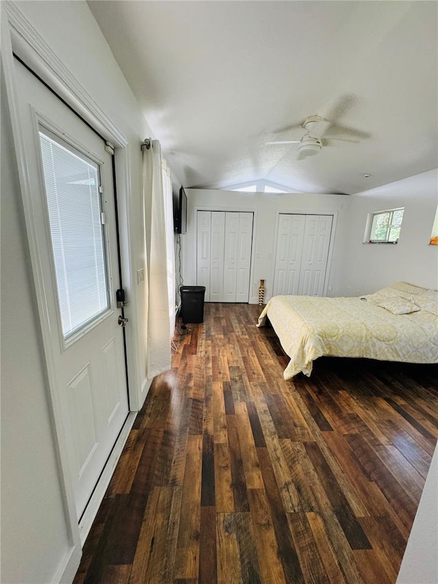 unfurnished bedroom featuring multiple closets, vaulted ceiling, ceiling fan, and dark hardwood / wood-style floors