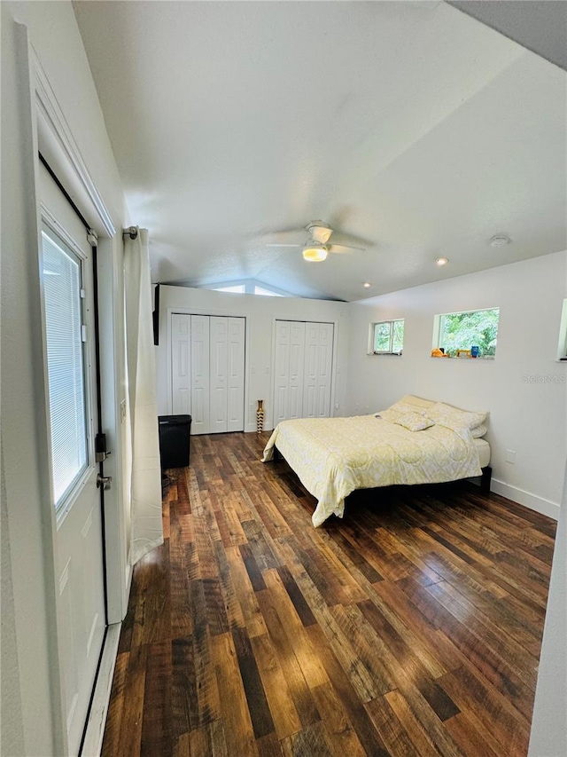 bedroom featuring ceiling fan, dark hardwood / wood-style floors, two closets, and multiple windows