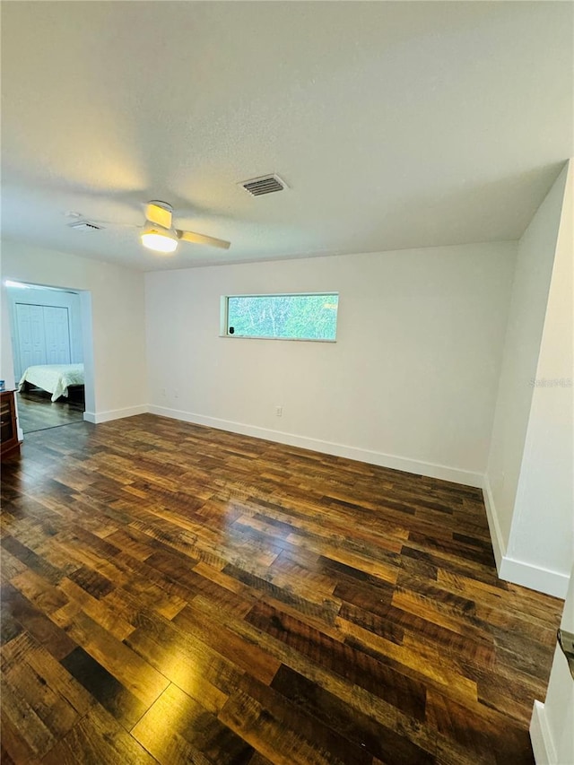 unfurnished room featuring dark wood-type flooring, a skylight, and ceiling fan