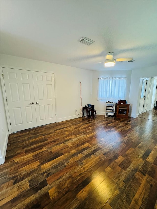 unfurnished bedroom featuring dark wood-type flooring, a closet, and ceiling fan