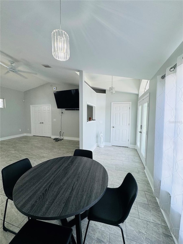 dining room featuring ceiling fan with notable chandelier and vaulted ceiling