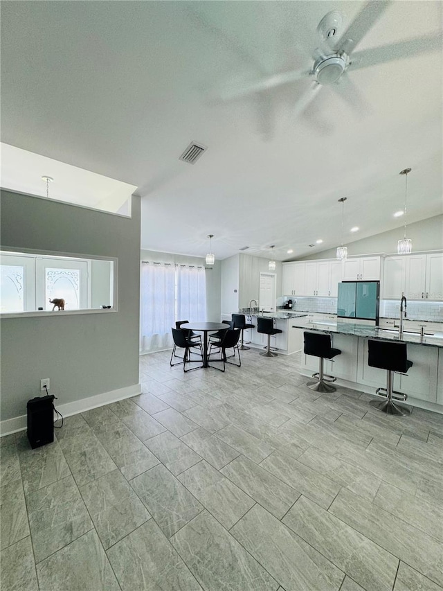 interior space with a wealth of natural light, ceiling fan, sink, and vaulted ceiling