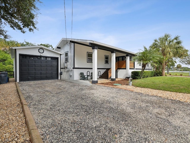 view of front of house featuring a front yard, a garage, a porch, and an outbuilding