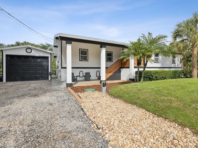 view of front of home with a porch, an outbuilding, a front lawn, and a garage