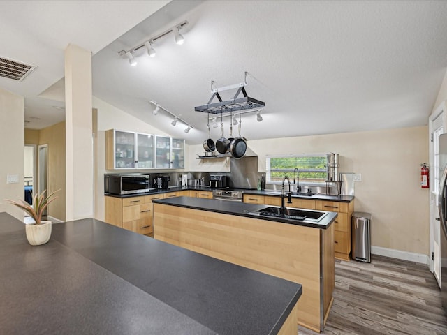 kitchen featuring light brown cabinets, lofted ceiling, wood-type flooring, rail lighting, and a center island