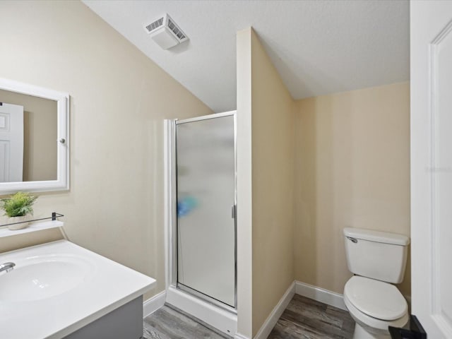 bathroom featuring lofted ceiling, vanity, hardwood / wood-style floors, walk in shower, and toilet