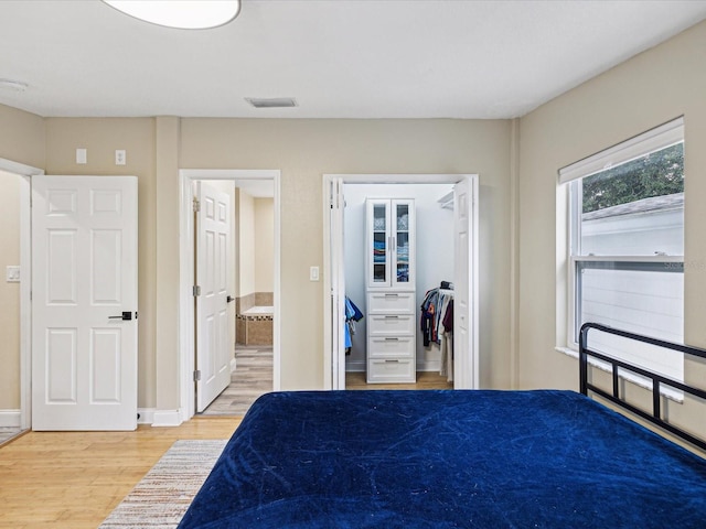 bedroom featuring a spacious closet, a closet, and wood-type flooring