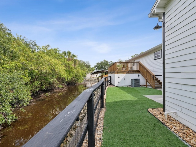 view of yard featuring cooling unit and a deck with water view