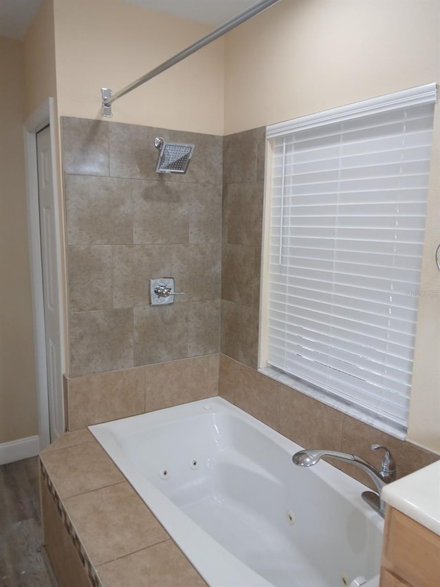 bathroom featuring tiled bath, vanity, and wood-type flooring