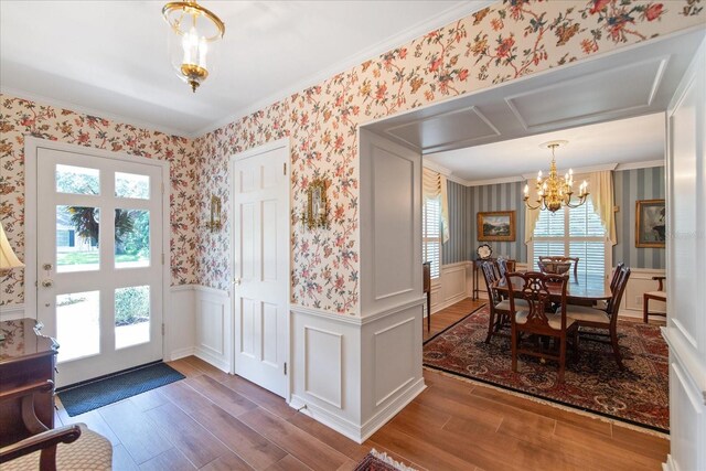 interior space featuring crown molding, wood-type flooring, an inviting chandelier, and a healthy amount of sunlight