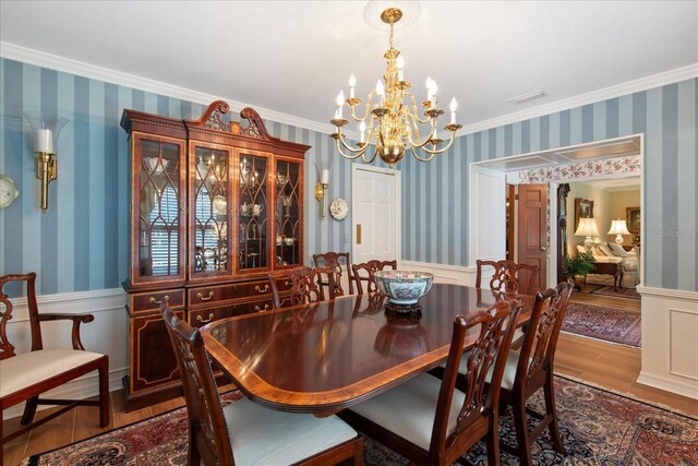 dining room featuring crown molding, wood-type flooring, and an inviting chandelier