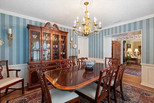 dining area featuring wallpapered walls, crown molding, wood finished floors, and wainscoting