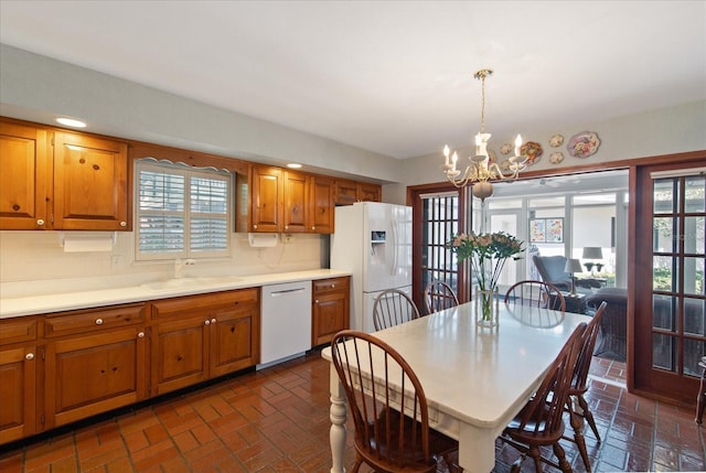 kitchen with pendant lighting, white appliances, a chandelier, sink, and decorative backsplash