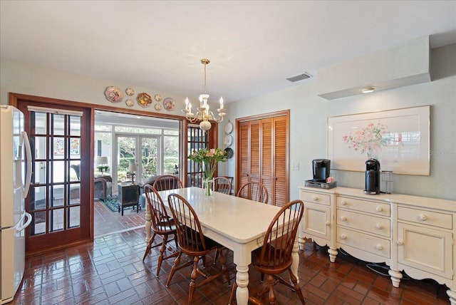 dining space featuring a chandelier, brick floor, and visible vents