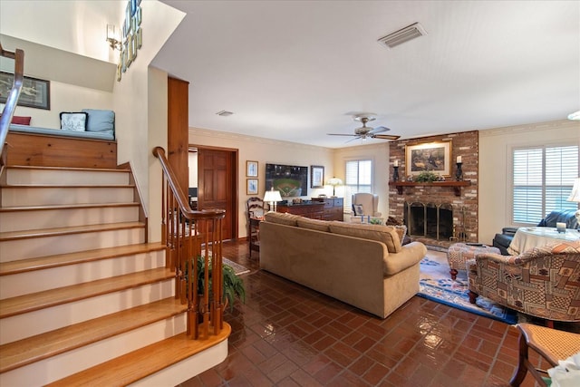 living room with crown molding, ceiling fan, and a brick fireplace