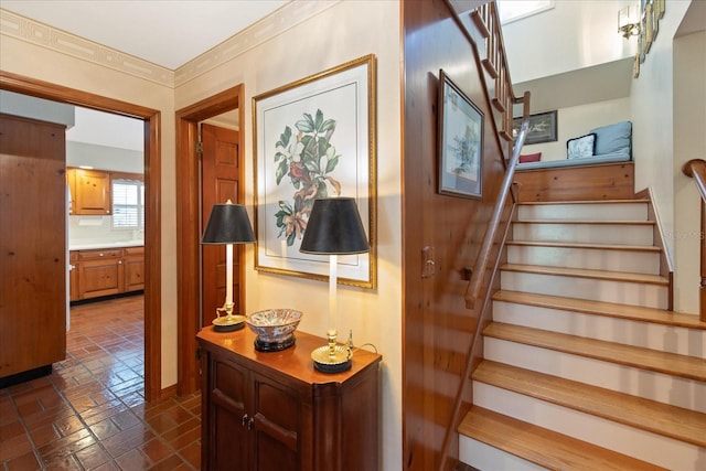 staircase with brick floor and crown molding