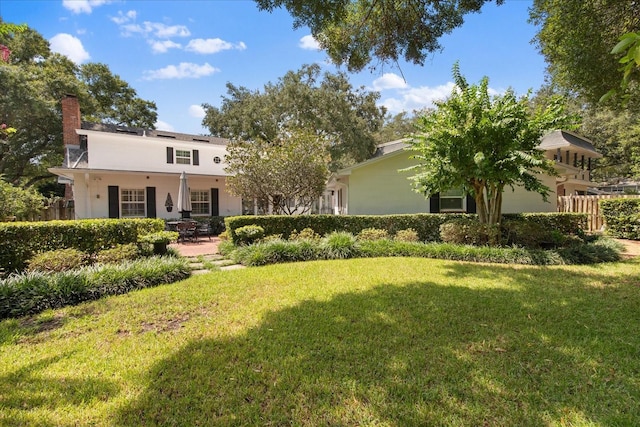 back of house with a patio, a chimney, stucco siding, a lawn, and fence