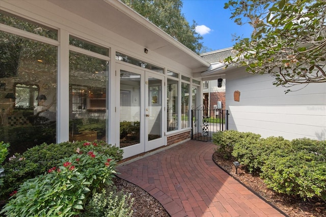 view of exterior entry with brick siding, roof with shingles, and french doors