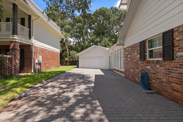 view of property exterior with a balcony, a garage, an outbuilding, and a lawn