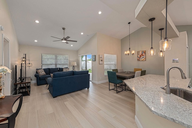 living area featuring light wood finished floors, baseboards, recessed lighting, ceiling fan with notable chandelier, and high vaulted ceiling