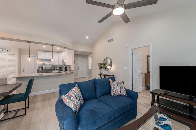 living area with vaulted ceiling, light wood-style flooring, visible vents, and ceiling fan