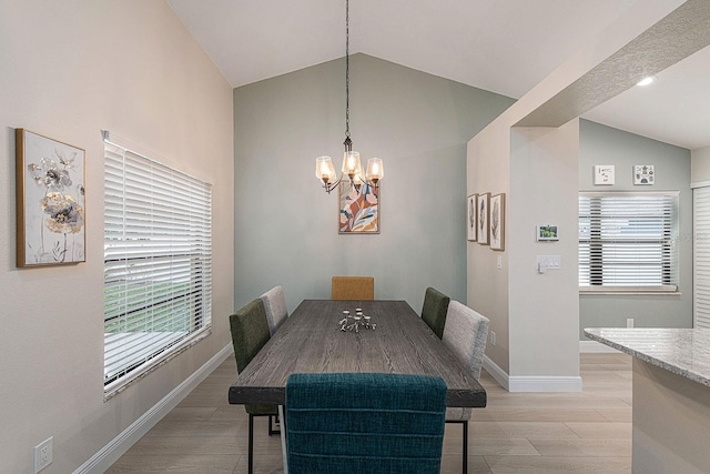 dining space featuring lofted ceiling, a wealth of natural light, a notable chandelier, and light wood finished floors