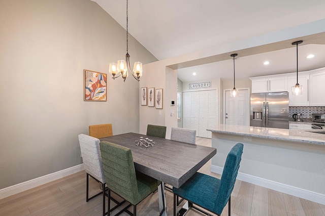 dining room with an inviting chandelier, vaulted ceiling, baseboards, and light wood-type flooring