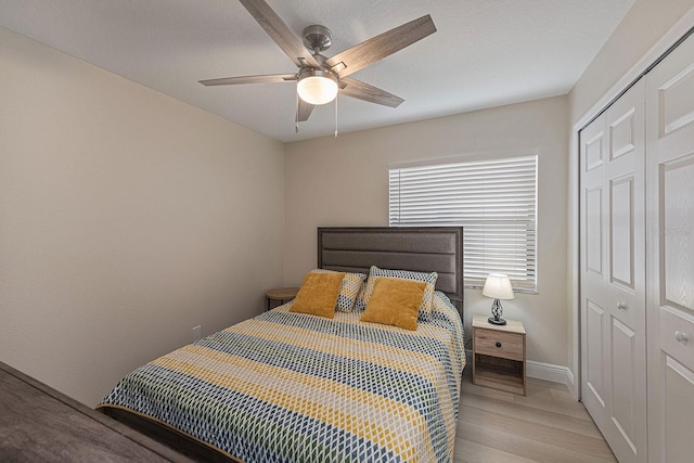 bedroom with light wood-style flooring, baseboards, a closet, and ceiling fan