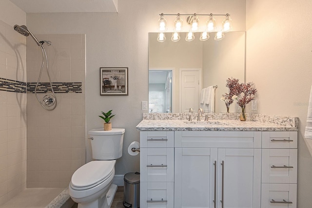 bathroom with toilet, vanity, and a tile shower