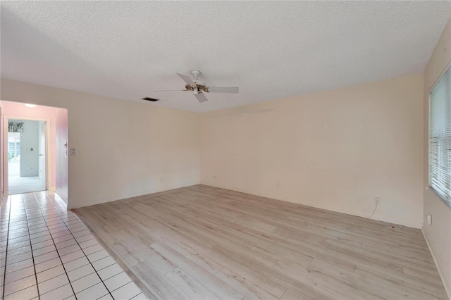 empty room with a textured ceiling, ceiling fan, and light wood-type flooring