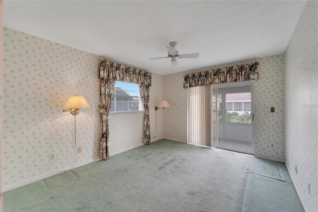 carpeted empty room with ceiling fan and a textured ceiling