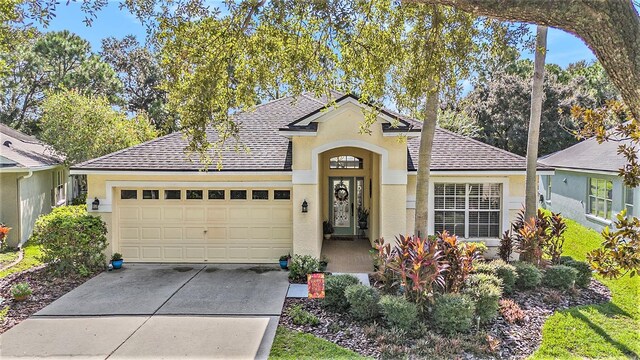 single story home with a shingled roof, concrete driveway, an attached garage, and stucco siding