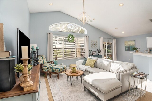 living room featuring lofted ceiling, a wealth of natural light, an inviting chandelier, and light hardwood / wood-style floors