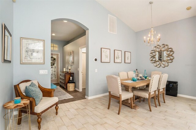 dining room with high vaulted ceiling, an inviting chandelier, and light hardwood / wood-style floors