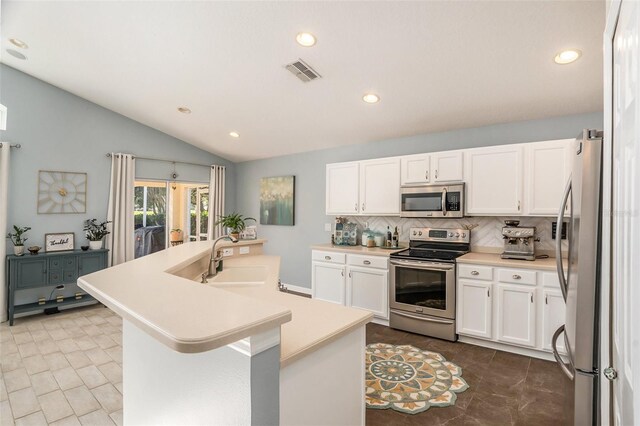 kitchen with appliances with stainless steel finishes, lofted ceiling, sink, and a center island with sink