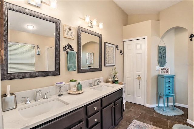 full bathroom with a sink, baseboards, and double vanity