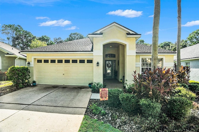 ranch-style house featuring driveway, roof with shingles, a garage, and stucco siding