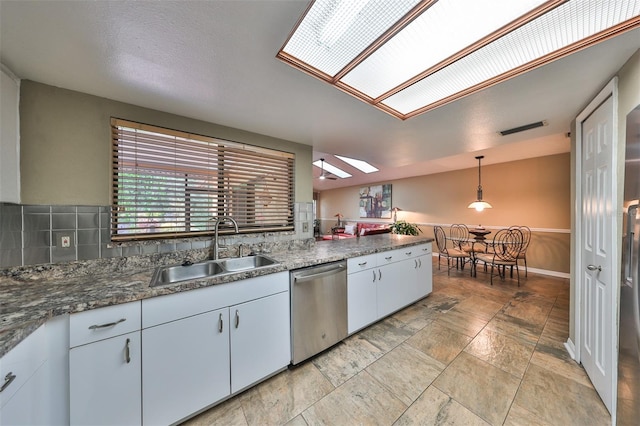 kitchen with a skylight, dishwasher, decorative light fixtures, white cabinetry, and sink