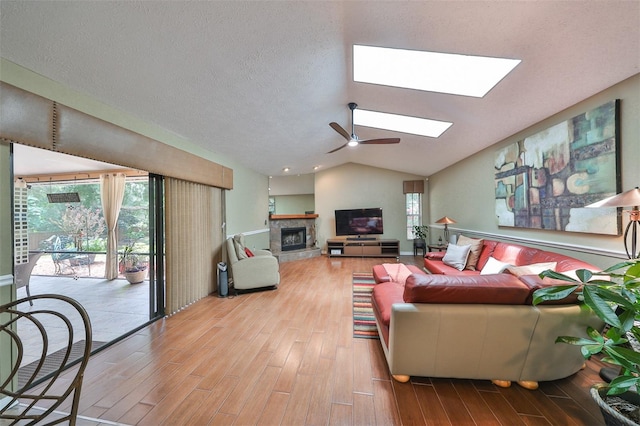 living room featuring hardwood / wood-style floors, ceiling fan, vaulted ceiling with skylight, and a healthy amount of sunlight