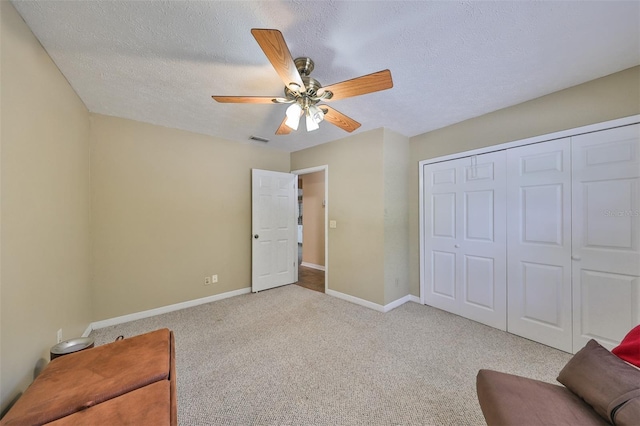 interior space with ceiling fan, light colored carpet, and a textured ceiling