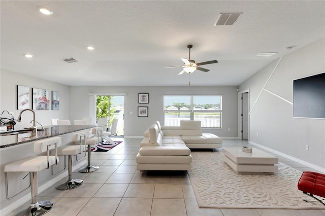 living room with ceiling fan, sink, a textured ceiling, and a healthy amount of sunlight