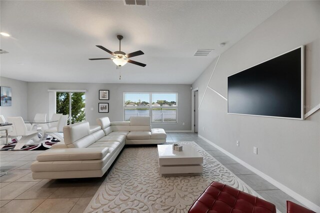 tiled living room with plenty of natural light and ceiling fan