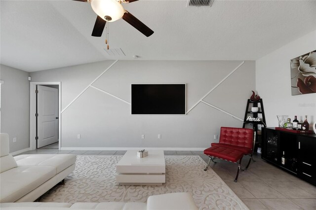 living room with lofted ceiling, ceiling fan, and light tile patterned floors