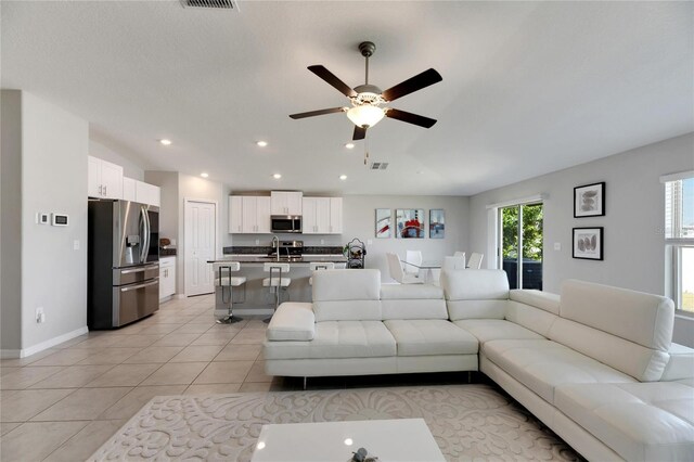 tiled living room with ceiling fan and sink