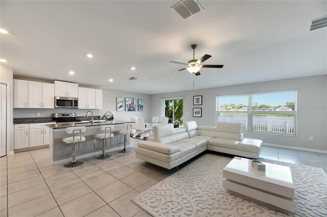 tiled living room featuring ceiling fan and sink