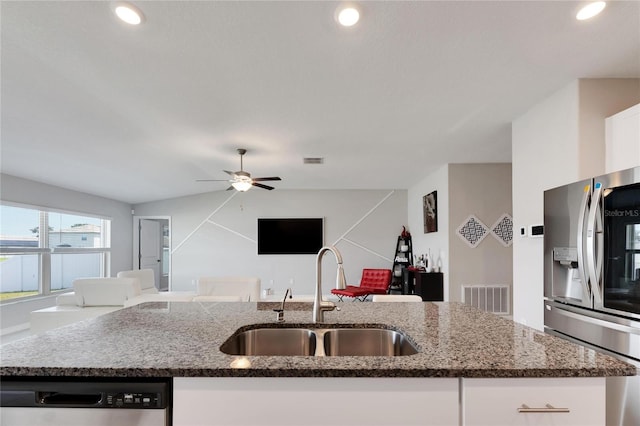 kitchen with an island with sink, stainless steel appliances, sink, white cabinetry, and ceiling fan