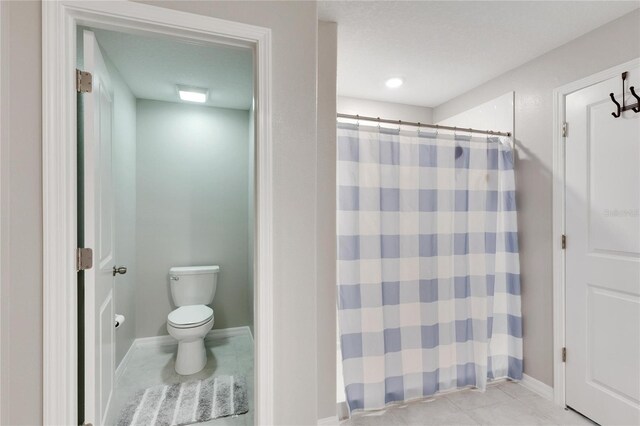 bathroom with a textured ceiling, toilet, and walk in shower