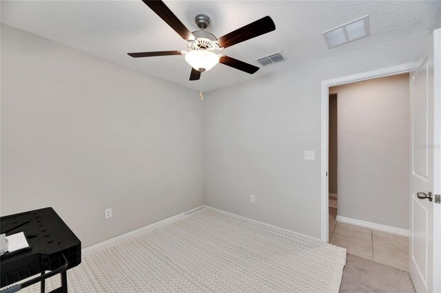 unfurnished room with a textured ceiling, ceiling fan, and light carpet