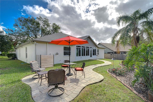 back of house with a lawn and a patio